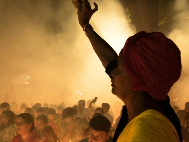 Crowd of ethnic people on street during Indian religious festival at night.