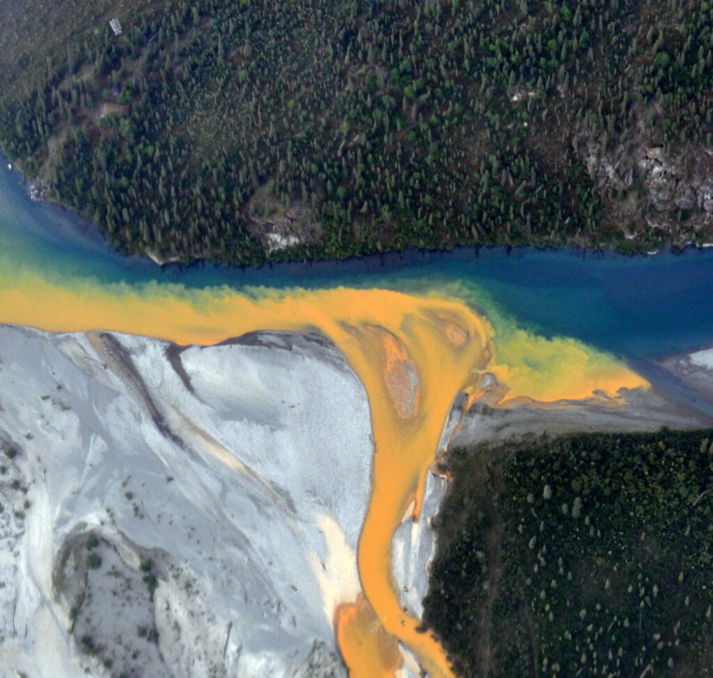 An aerial view of the Kutuk River in Alaska's Gates of the Arctic National Park that looks like orange paint spilling into the clear blue water. Ken Hill / National Park Service)