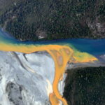 An aerial view of the Kutuk River in Alaska's Gates of the Arctic National Park that looks like orange paint spilling into the clear blue water. Ken Hill / National Park Service)