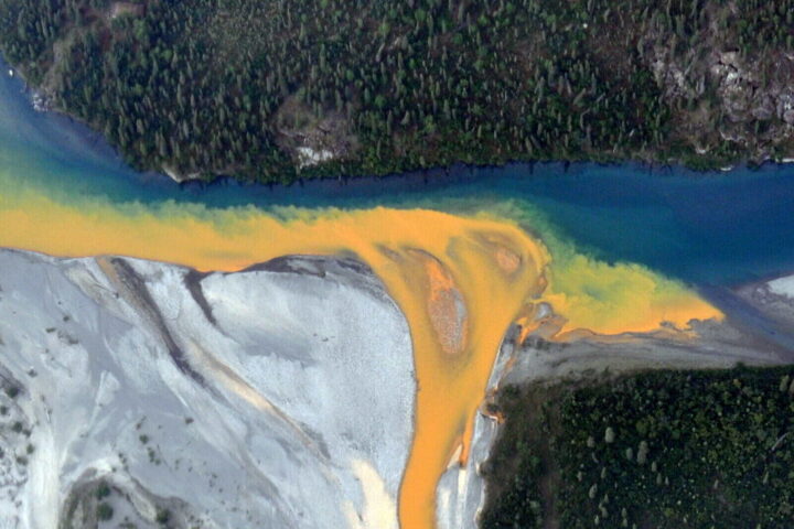 An aerial view of the Kutuk River in Alaska's Gates of the Arctic National Park that looks like orange paint spilling into the clear blue water. Ken Hill / National Park Service)