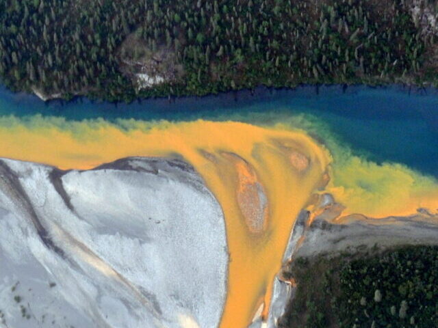 An aerial view of the Kutuk River in Alaska's Gates of the Arctic National Park that looks like orange paint spilling into the clear blue water. Ken Hill / National Park Service)