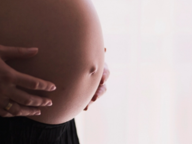 Pregnant woman in black holds her exposed stomach expectantly. Photo Source: RawPixel {CC0 1.0 DEED}