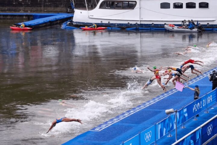 Athletes dive into the water at the start of a swimming event during the 2024 Summer Olympics in Paris. Photo Credits: @jacobsjasper @tzaferes @worldtriathlon (Instagram)