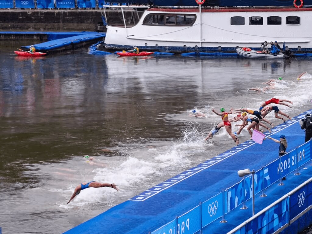 Athletes dive into the water at the start of a swimming event during the 2024 Summer Olympics in Paris. Photo Credits: @jacobsjasper @tzaferes @worldtriathlon (Instagram)