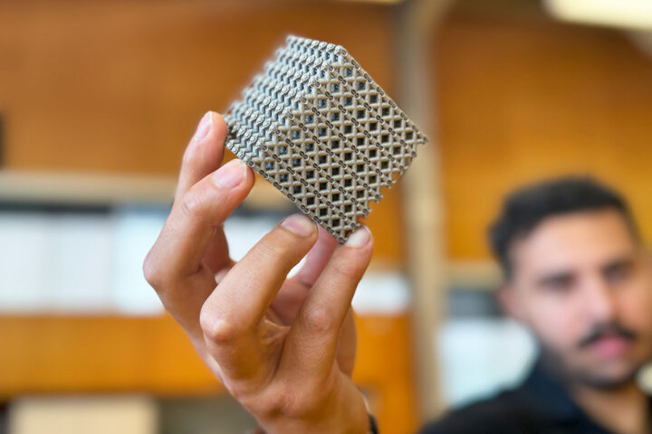 PhD candidate Jordan Noronha holding a sample of the new titanium lattice structure 3D printed in cube form.