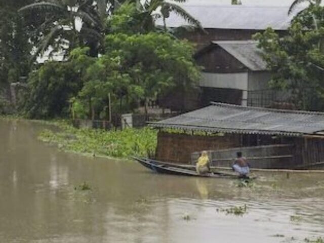 Villagers use a boat to travel across a flood affected area after heavy rainfall.