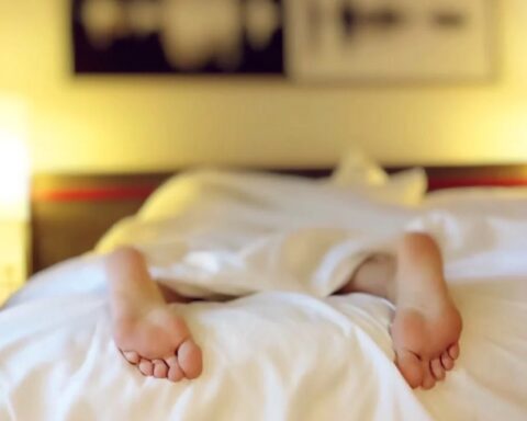 Person Lying on Bed Covering White Blanket.