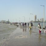 The Haji Ali Causeway, People walking out to Haji Ali Dargah along the causeway. Mumbai skyline in the background. Photot Source: Rakesh Krishna Kumar (Flicker)