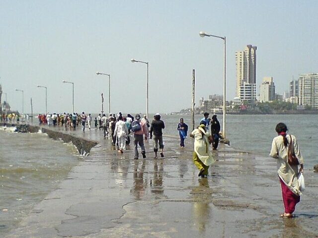 The Haji Ali Causeway, People walking out to Haji Ali Dargah along the causeway. Mumbai skyline in the background. Photot Source: Rakesh Krishna Kumar (Flicker)