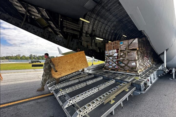 An Air National Guard member unloads food and water from a C-17 aircraft for distribution to residents impacted by Hurricane Helene in Asheville.