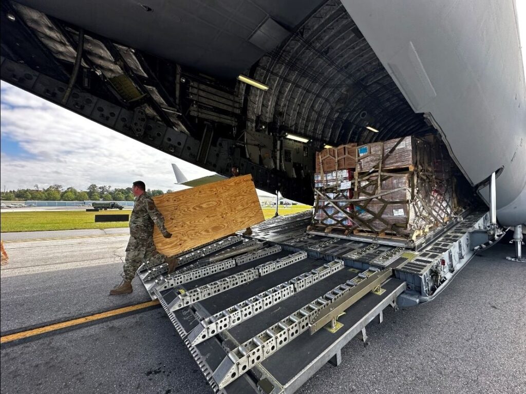 An Air National Guard member unloads food and water from a C-17 aircraft for distribution to residents impacted by Hurricane Helene in Asheville.