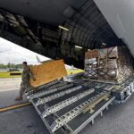 An Air National Guard member unloads food and water from a C-17 aircraft for distribution to residents impacted by Hurricane Helene in Asheville.