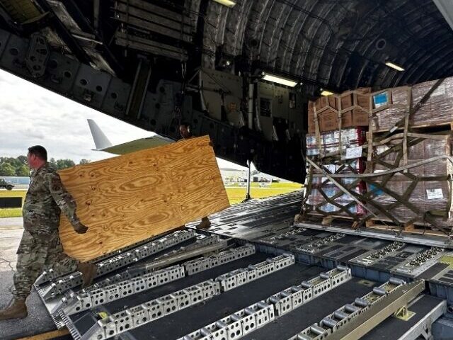 An Air National Guard member unloads food and water from a C-17 aircraft for distribution to residents impacted by Hurricane Helene in Asheville.