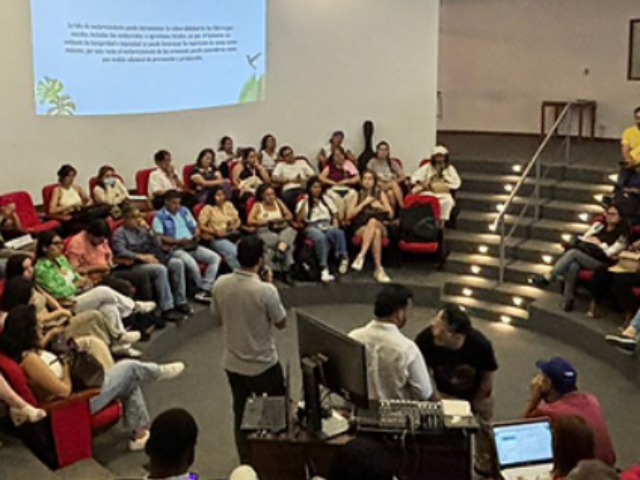 A group of people seated in a semi-circular arrangement in an auditorium or lecture hall.