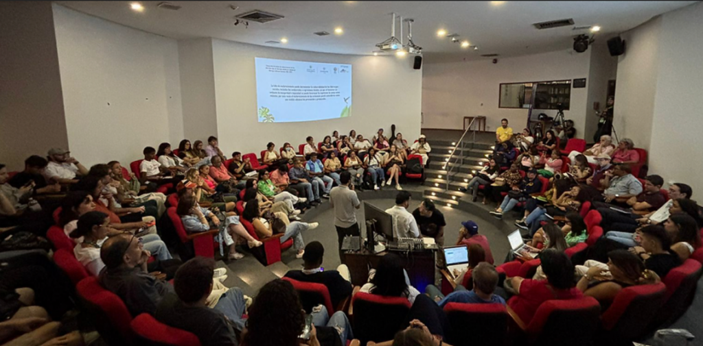 A group of people seated in a semi-circular arrangement in an auditorium or lecture hall.