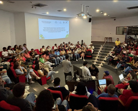 A group of people seated in a semi-circular arrangement in an auditorium or lecture hall.