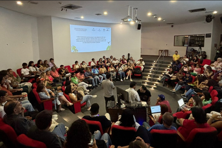 A group of people seated in a semi-circular arrangement in an auditorium or lecture hall.