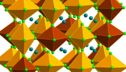 Structure of the gold-halide perovskite. The elongated gold-chloride octahedra, composed of gold (Au) surrounded by six neighboring chlorine (Cl) atoms, are shaded in the structure: burnt-red octahedra represent Au2+-chloride and gold octahedra represent Au3+-chloride. Turquoise spheres represent cesium (Cs) atoms, and light- green spheres represent chlorine (Cl) atoms. The inset shows the shortest gold-chloride bonds. Image credit Karunadasa et al. 2023.