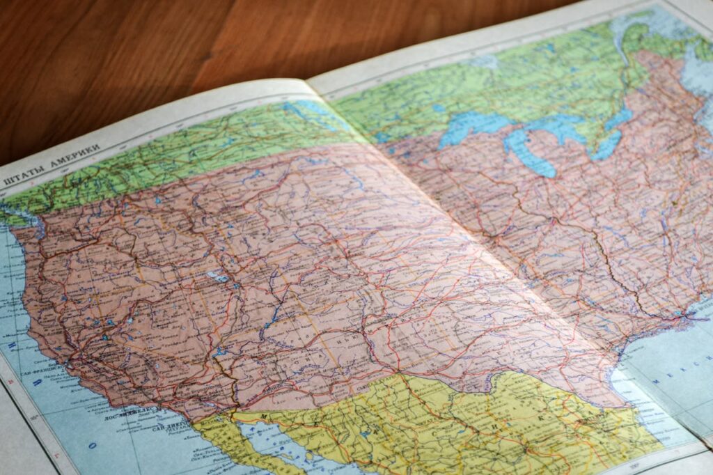 Representative Image. Map of the World Book Laid Open on Brown Wooden Surface. Photo Source: John-Mark Smith (Pexels)