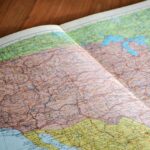 Representative Image. Map of the World Book Laid Open on Brown Wooden Surface. Photo Source: John-Mark Smith (Pexels)