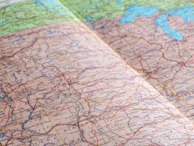 Representative Image. Map of the World Book Laid Open on Brown Wooden Surface. Photo Source: John-Mark Smith (Pexels)