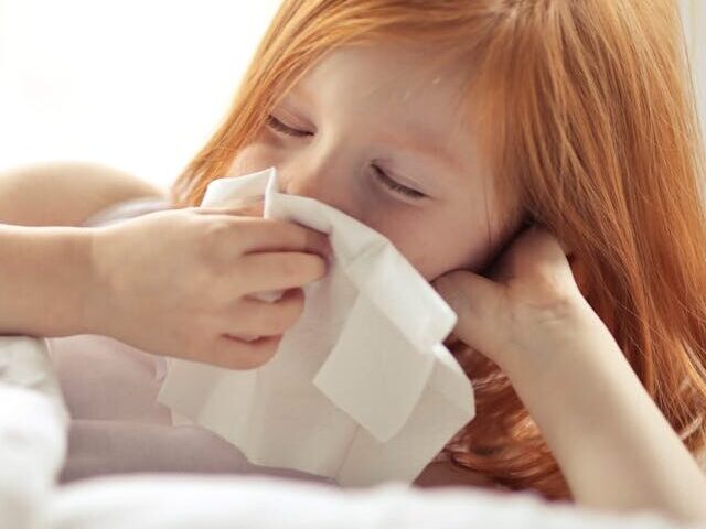 Representative Image. A sick girl wiping her nose with tissue. Photo Source: Andrea Piacquadio (Pexels)