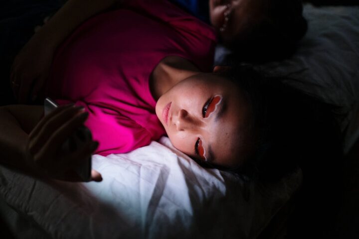 Representative Iimage. a person lying on a bed, holding a mobile phone.