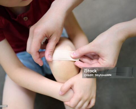 Representative Image. Mother hands applying antibacterial medical adhesive bandage on child's knee after falling down. First aid for kids after injury/trauma. Photo Source: SbytovaMN (IStock)