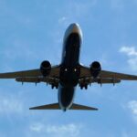 An airplane against a blue sky with clouds. Photo Source: xlibber (CC BY 2.0)