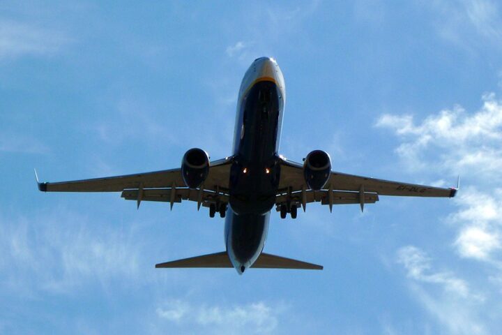 An airplane against a blue sky with clouds. Photo Source: xlibber (CC BY 2.0)