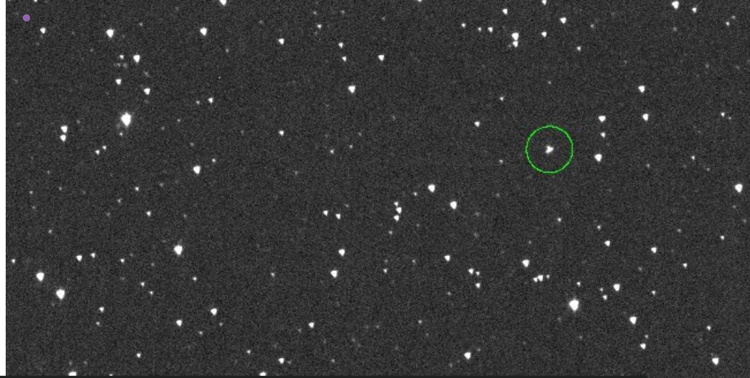 A telescope-captured view of space showing multiple stars or celestial objects. A particular object is highlighted with a green circle, which likely represents the asteroid 2024 YR4. Photo Source: NASA