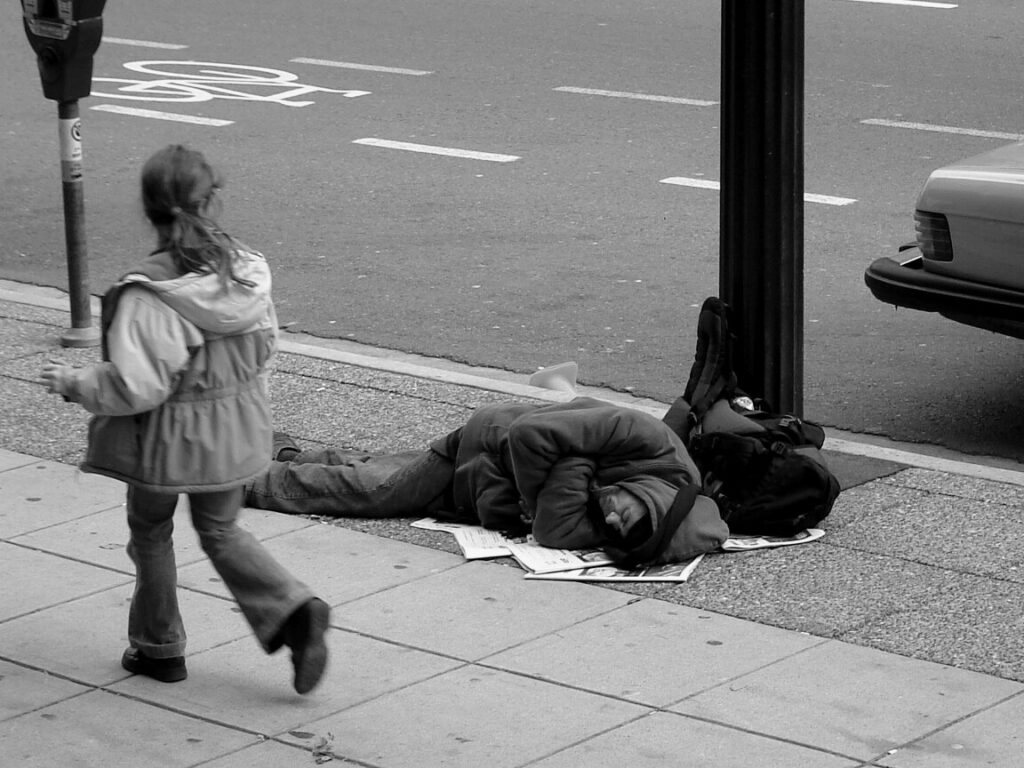 Man sleeping on Canadian sidewalk. Photo Source: The Blackbird (Jay Black) (CC BY-SA 2.0).