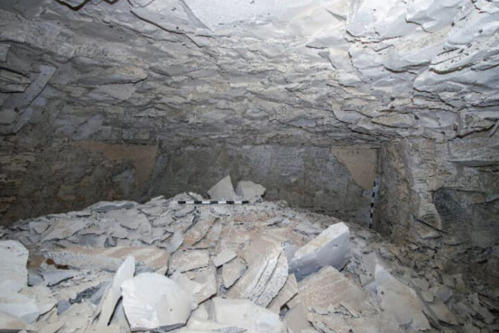 Rock-filled cave interior with measuring stick. Photo Source: Ministry of Tourism and Antiquities.