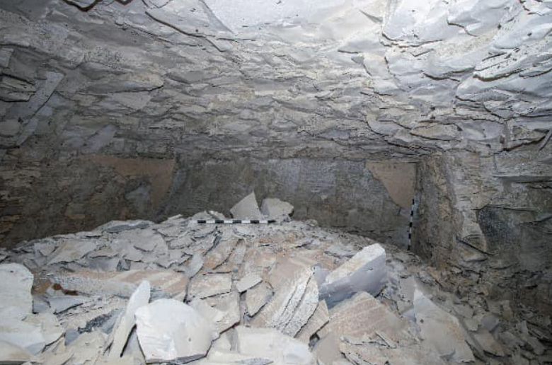 Rock-filled cave interior with measuring stick. Photo Source: Ministry of Tourism and Antiquities.