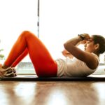 Representative Image: Woman Wearing Orange Leggings and White Tank Top Doing Pull-ups.