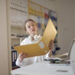 Female office worker with folder in workplace.Photo Source:Andrea Piacquadio (Pexels)