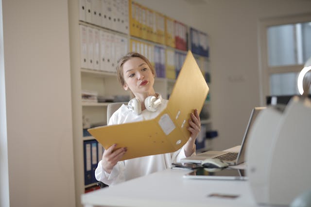 Female office worker with folder in workplace.Photo Source:Pexels