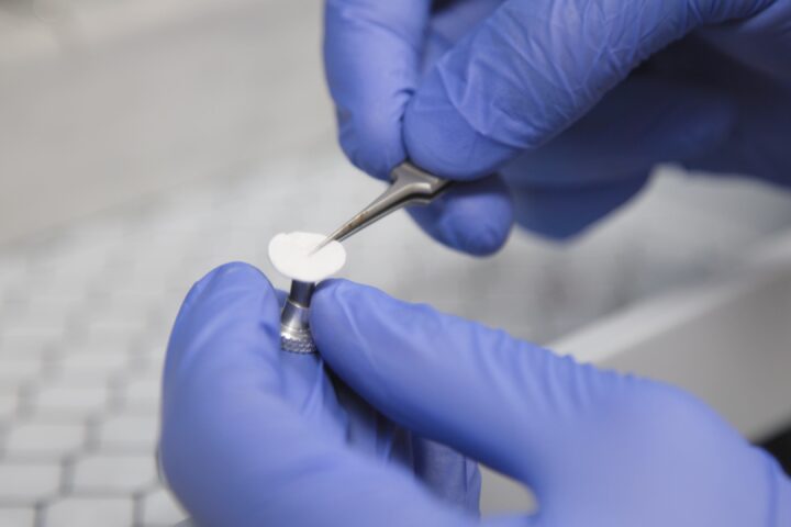 Representative image, Gloved hands carefully handle a small, white sample with tweezers. Photo Source: (hsc.unm.edu/news)