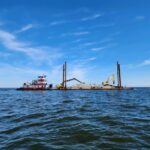 Open ocean with a barge carrying construction equipment. Photo Source: Stevens Towing