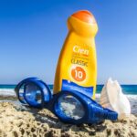 Representative image. Sunscreen, goggles, and seashell on a rocky beach. Photo Source: Dimitrisvetsikas1969.