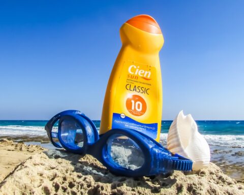 Representative image. Sunscreen, goggles, and seashell on a rocky beach. Photo Source: Dimitrisvetsikas1969.