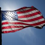 Representative Image: Flag of the United States of America waving against a clear blue sky. Photo Source: Jnn13 (CC BY-SA 3.0)