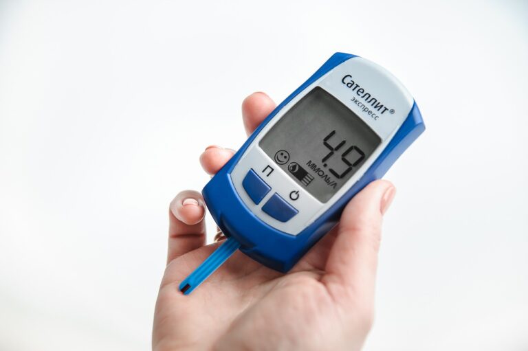 Representative image, A hand holds a blue and white "Satelit Express" glucose meter displaying a reading of "4.9 mmol/L". Photo Source: Stanias.