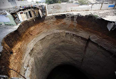 Representative Image: Massive sinkhole in an urban area, with buildings on the edge of the collapse. Photo Sourse: John C Bullas BSc MSc PhD MCIHT MIAT (CC BY-NC-ND 2.0)