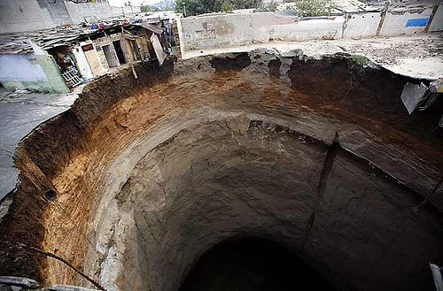 Representative Image: Massive sinkhole in an urban area, with buildings on the edge of the collapse. Photo Sourse: John C Bullas BSc MSc PhD MCIHT MIAT (CC BY-NC-ND 2.0)