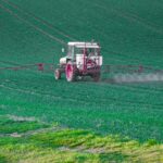 Representative Image: A tractor with a pesticide sprayer attached, working on a vast green agricultural field. The tractor is dispersing chemicals across the crops, likely for pest control, fertilization, or weed management. Photo source: needpic.com (maxmann (pixabay.com))