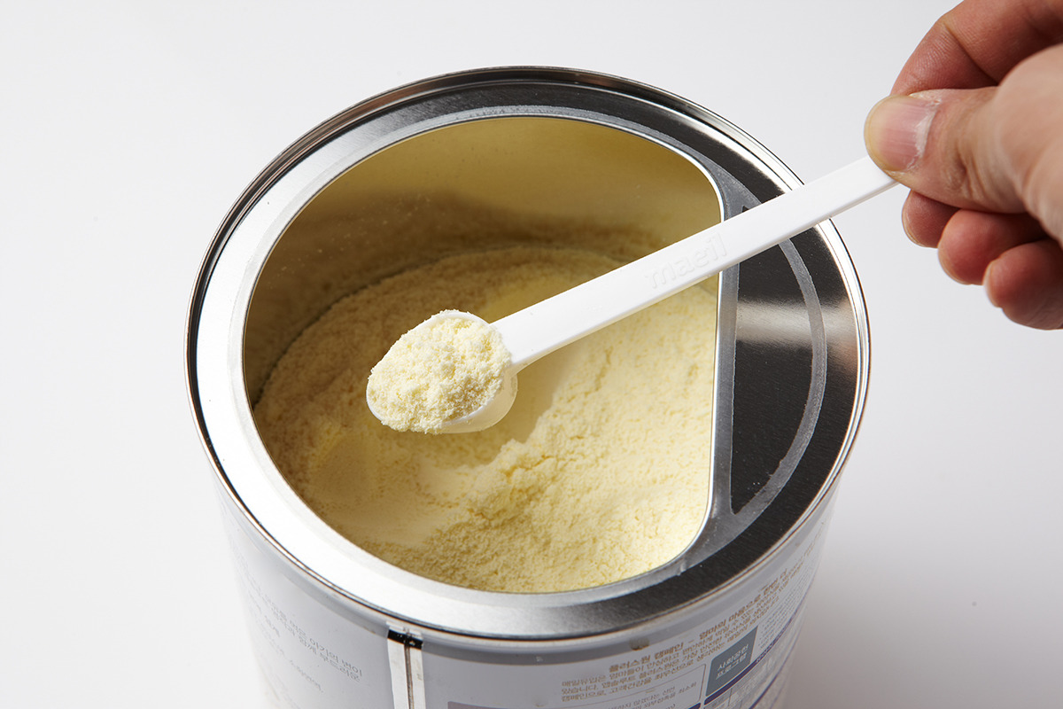 Representative Image. A hand holding a white plastic scoop filled with powdered formula. Photo Source - 국립국어원 (CC BY-SA 2.0 KR)