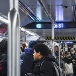 A crowded subway train with passengers standing and holding onto poles. The overhead digital sign displays "G" and "35 ST.", indicating that this is an MTA G Line train in New York City. Photo Source: MTA (https://www.mta.info/)