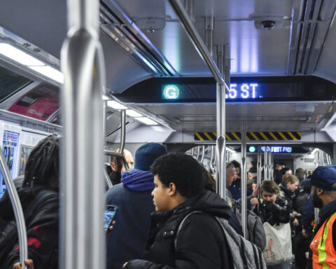 A crowded subway train with passengers standing and holding onto poles. The overhead digital sign displays "G" and "35 ST.", indicating that this is an MTA G Line train in New York City. Photo Source: MTA (https://www.mta.info/)