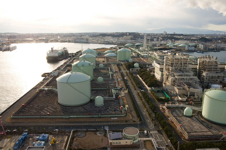 Representative Image: An industrial port facility with large storage tanks, pipelines, and processing units, related to liquefied natural gas (LNG) or petrochemical storage. Photo Source: Σ64 (CC BY 3.0)